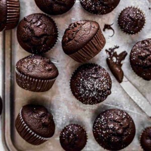 a dozen chocolate muffins on a silver tray