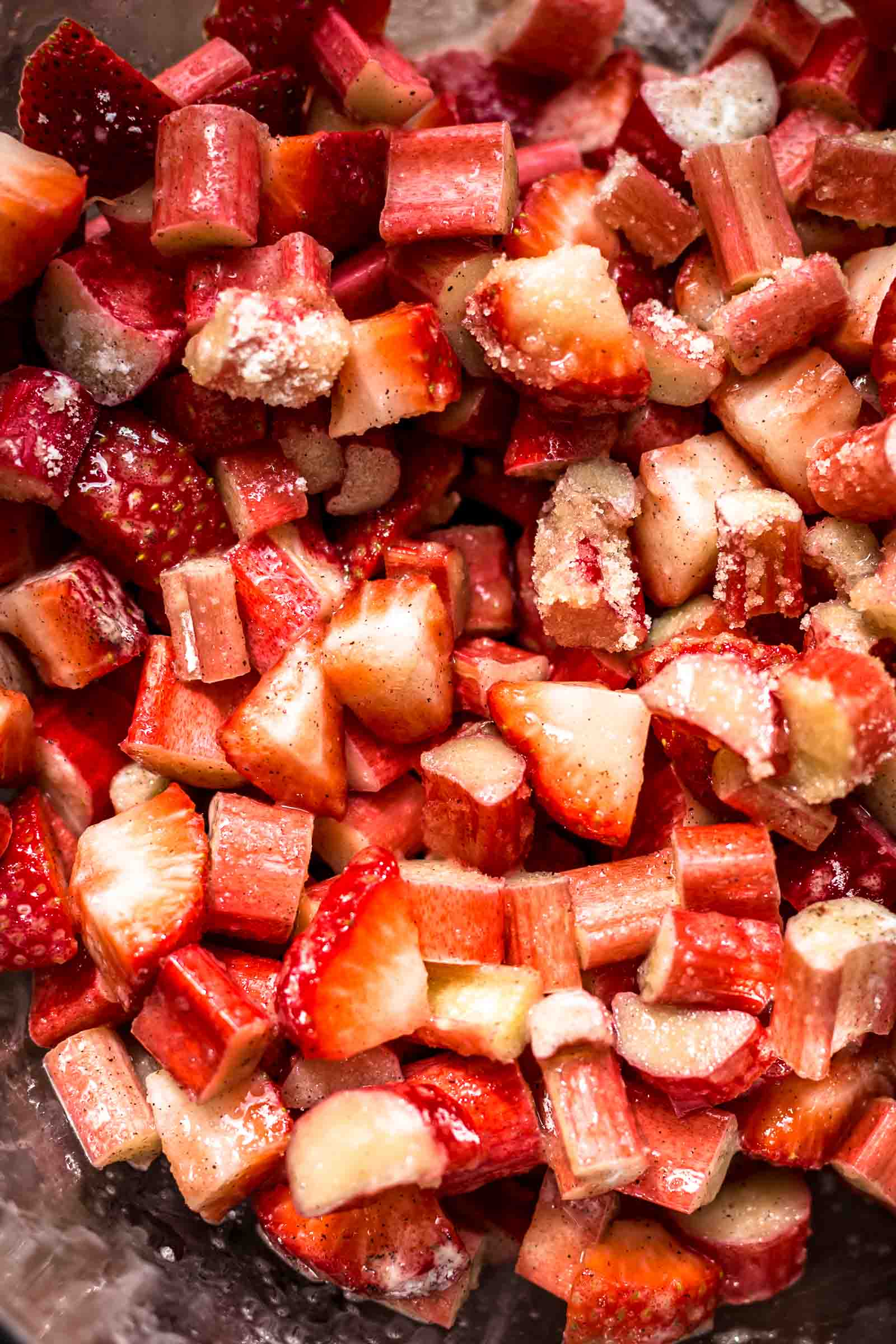 chopped strawberries and rhubarb covered in sugar in a mixing bowl