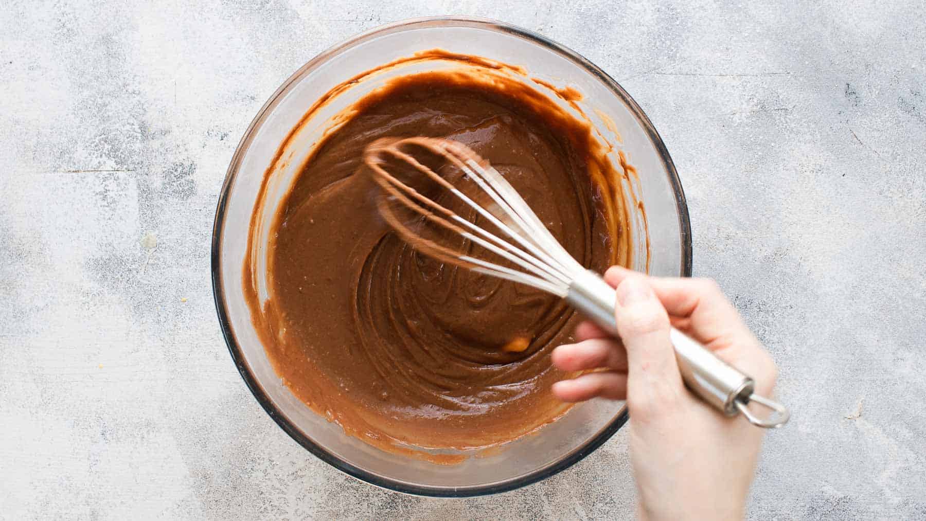 whisking chocolate cream filling with a whisk in a large mixing bowl