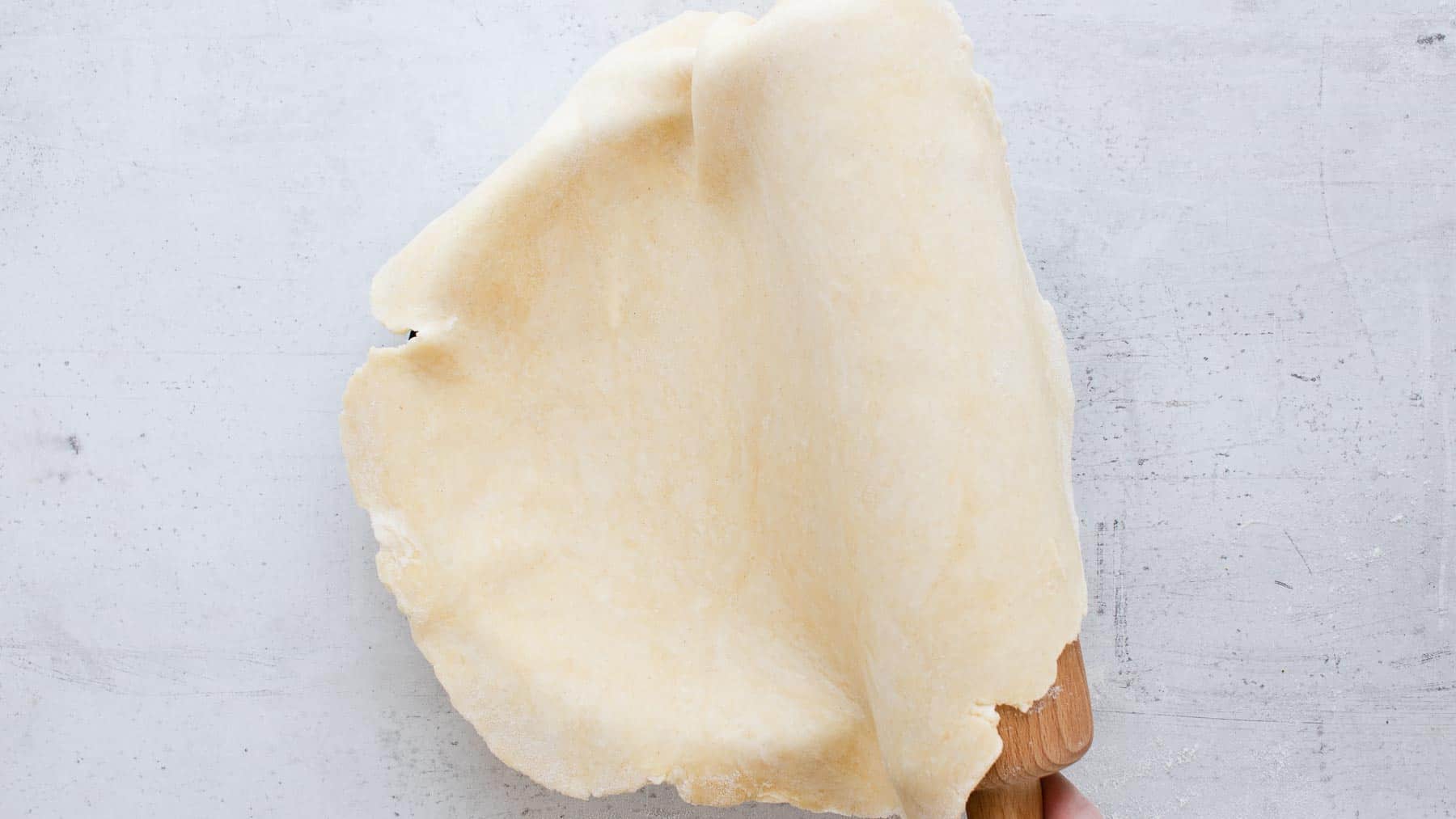 transferring rolled out pie crust with a rolling pin to a pie dish