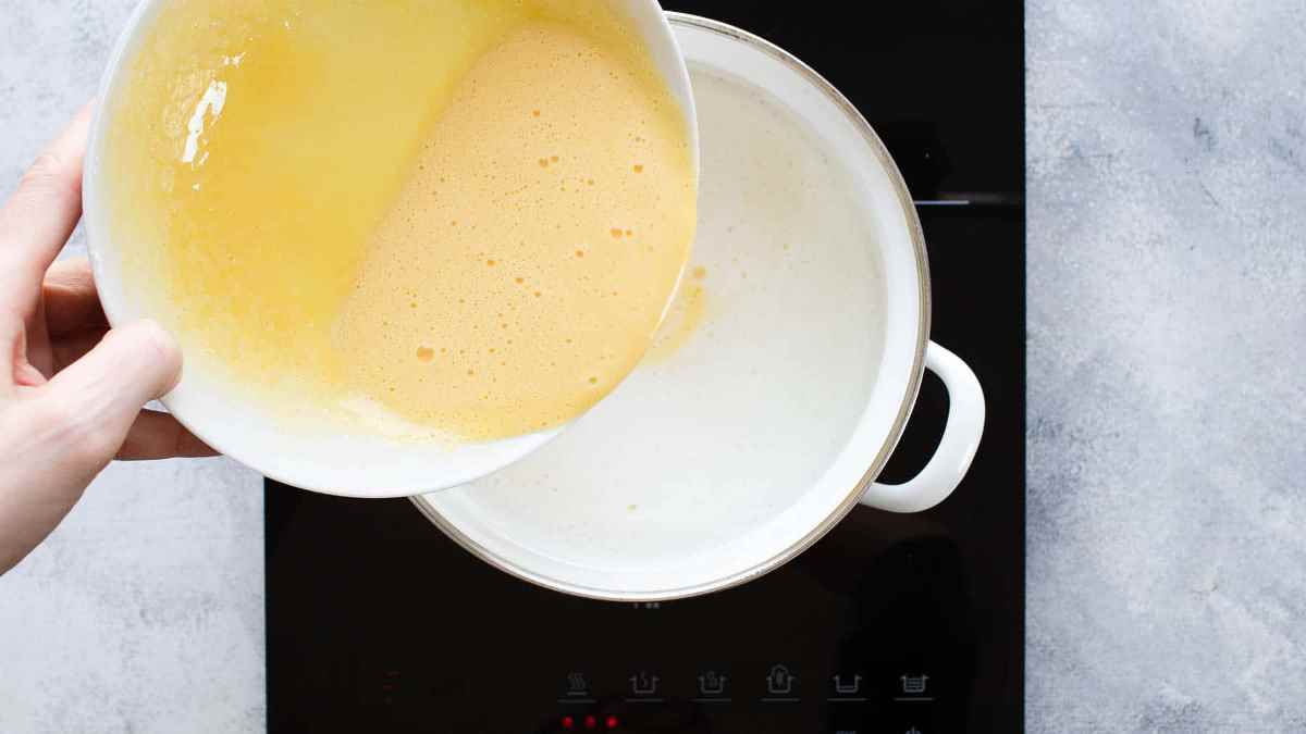 Whisk hot milk into the egg yolks 