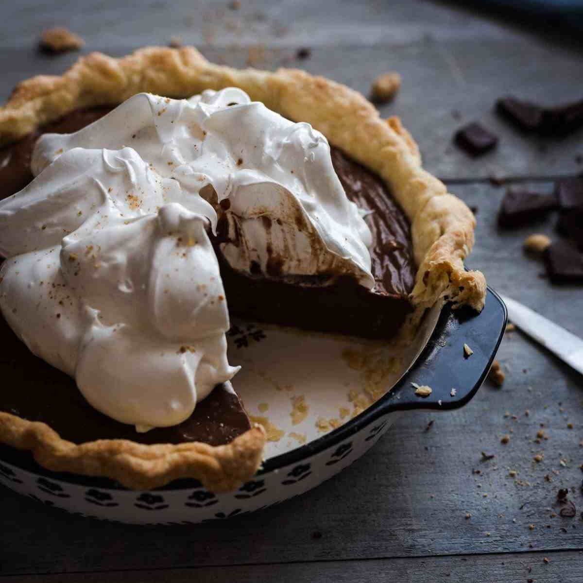 easy chocolate cream pie topped with meringue and a quarter missing sitting on a wooden table
