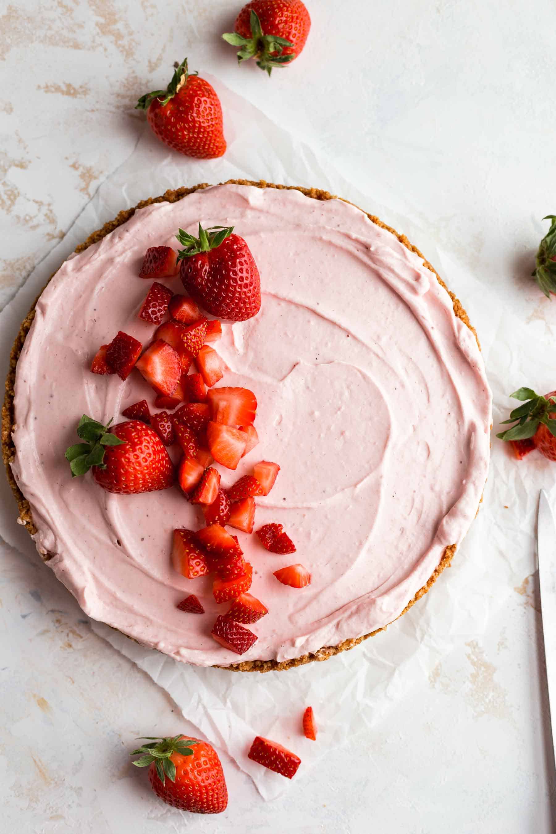 ready-to-serve strawberry cheesecake on a table with fresh strawberries on top