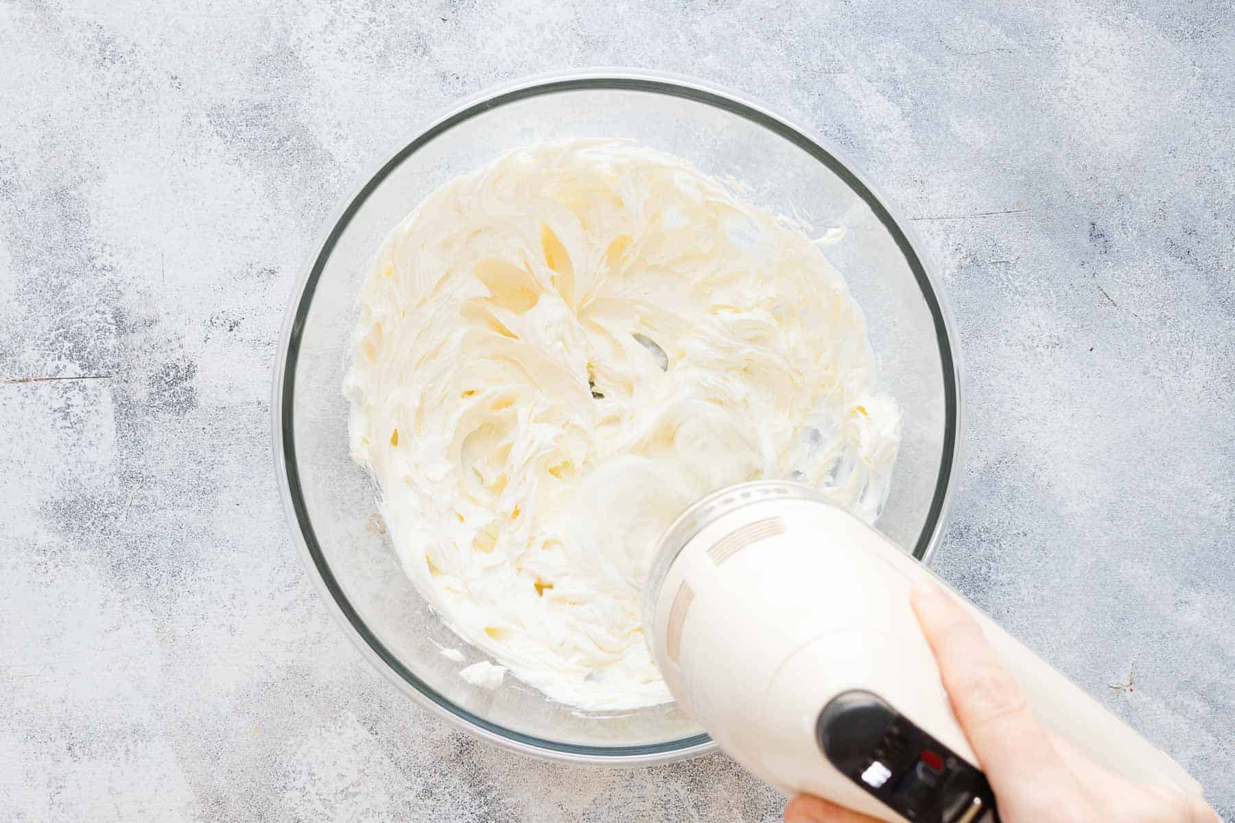 mixing cream cheese with an electric mixer