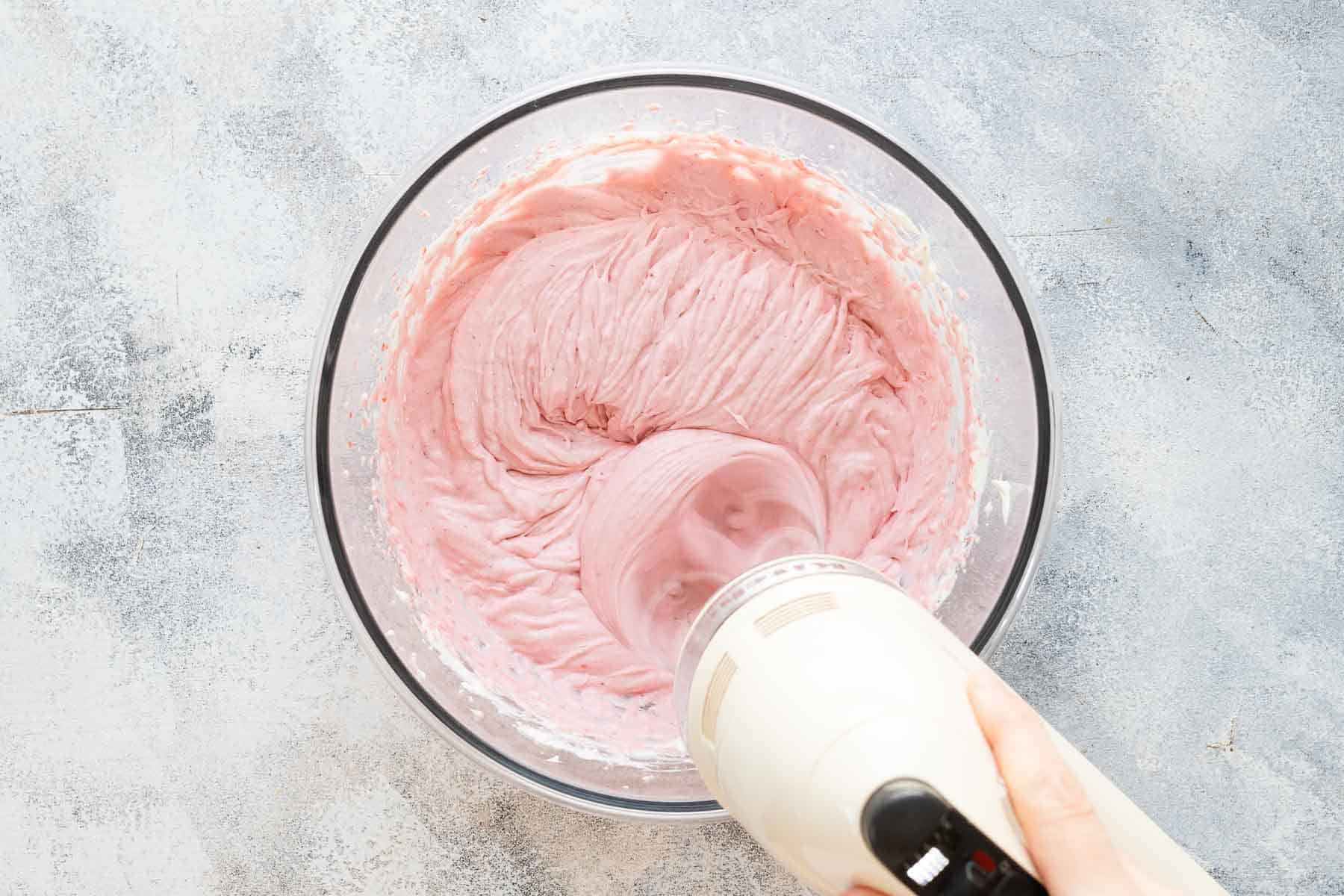 mixing strawberry puree into cream cheese with mixer