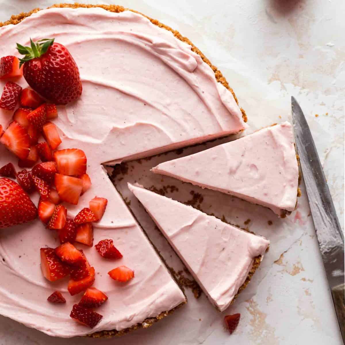 strawberry cheesecake with two slices cut out and strawberries on top