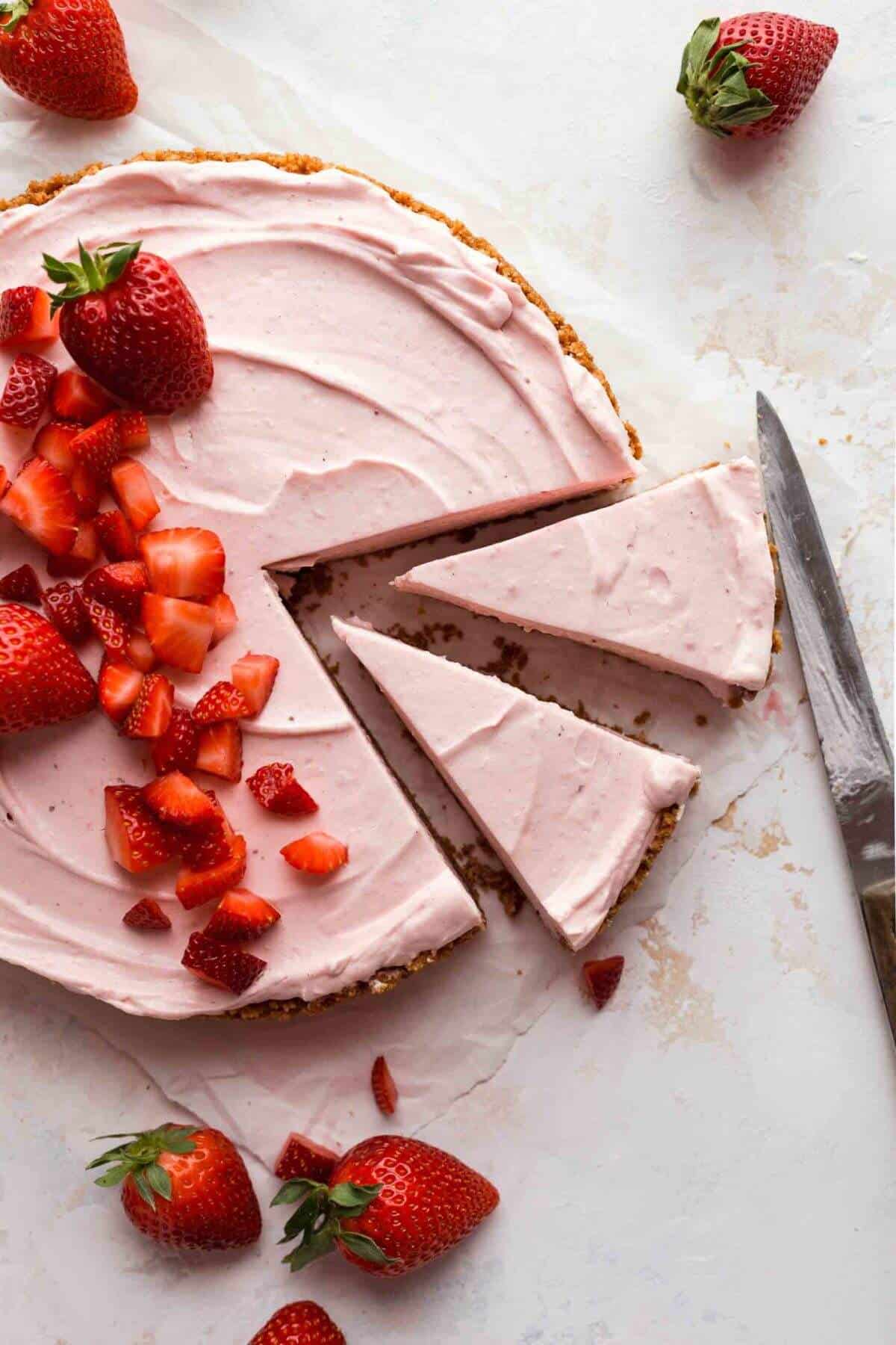 strawberry cheesecake with two slices cut out and strawberries on top