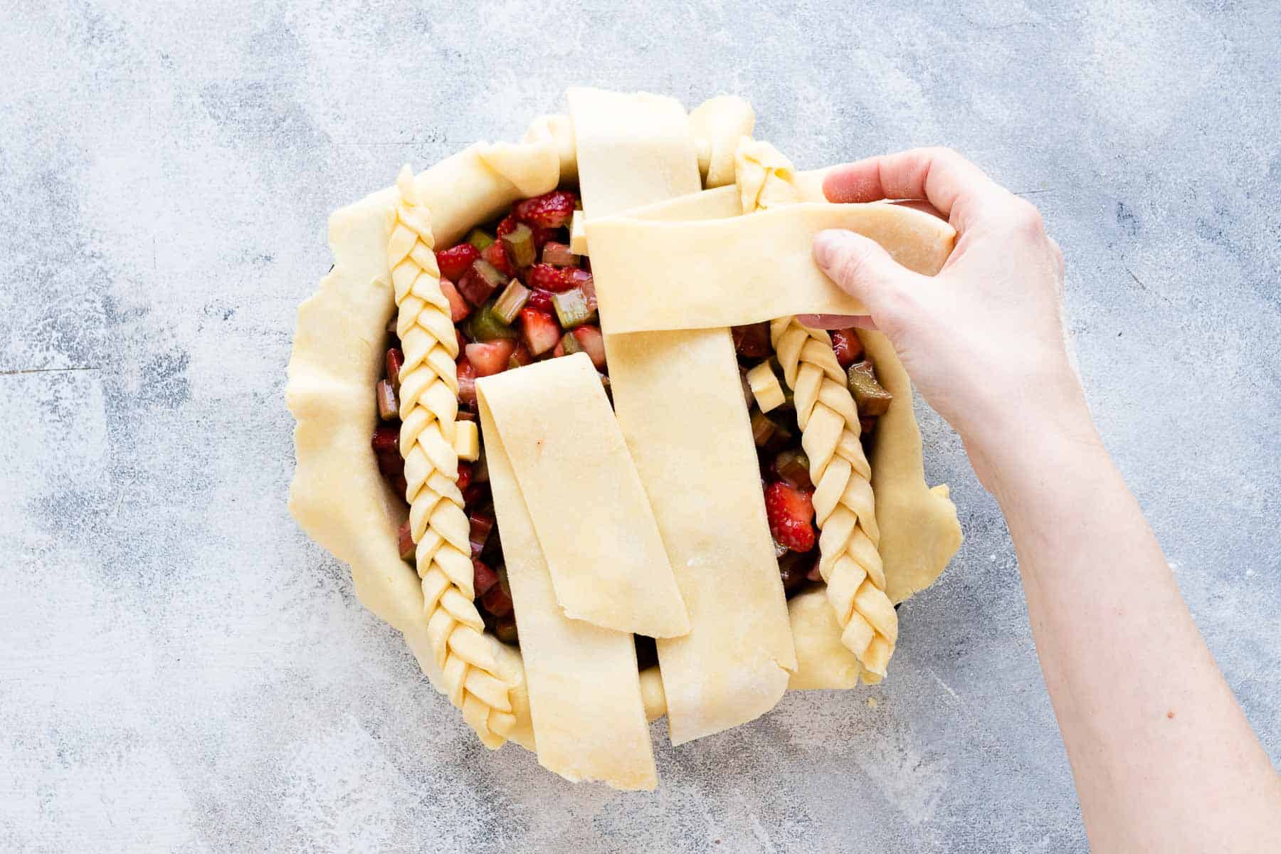 arranging braided pie crust strips onto filled, unbaked pie