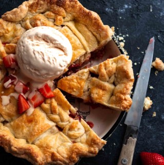 a whole strawberry rhubarb pie with ice cream dollop on it