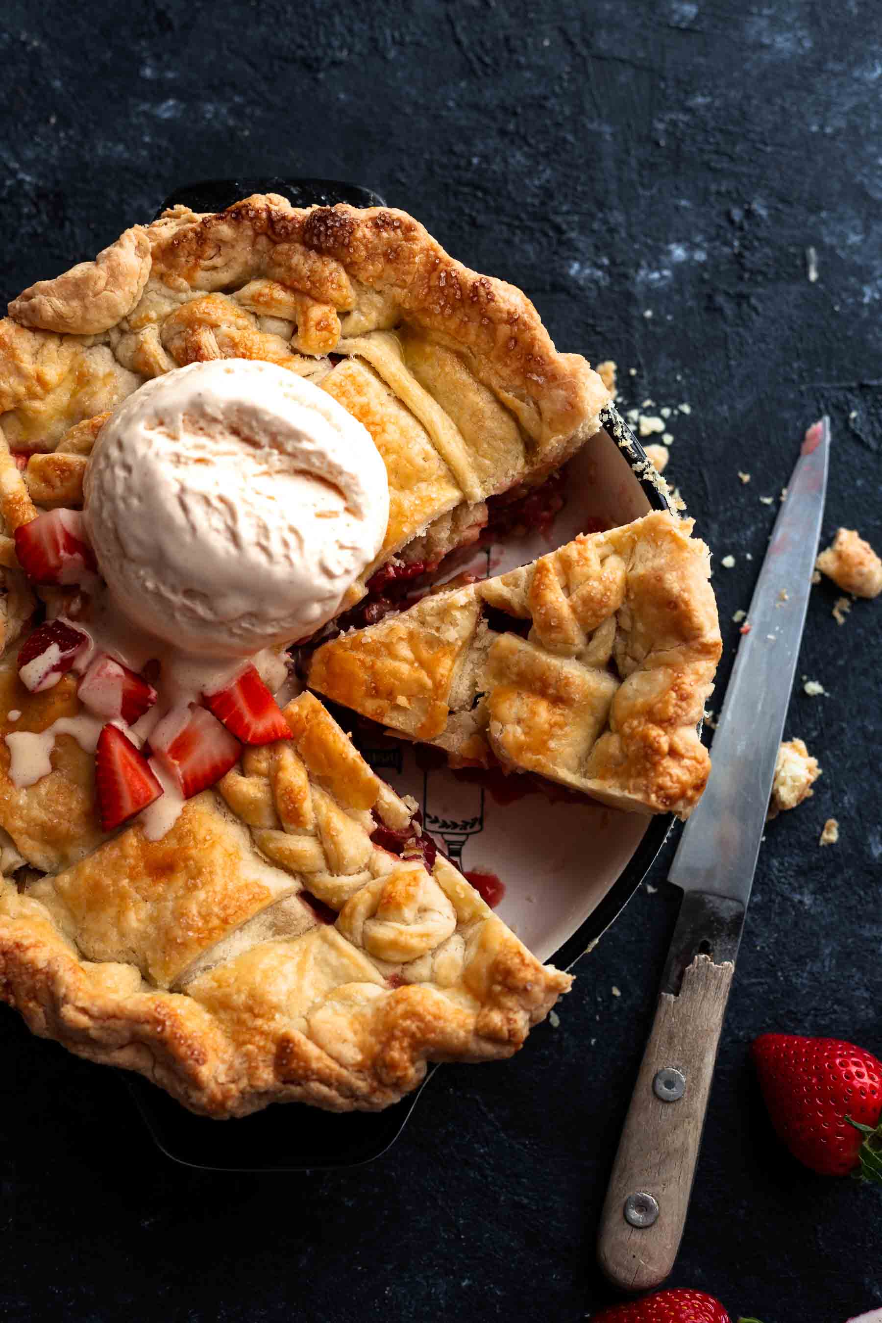 a whole strawberry rhubarb pie with ice cream dollop on it