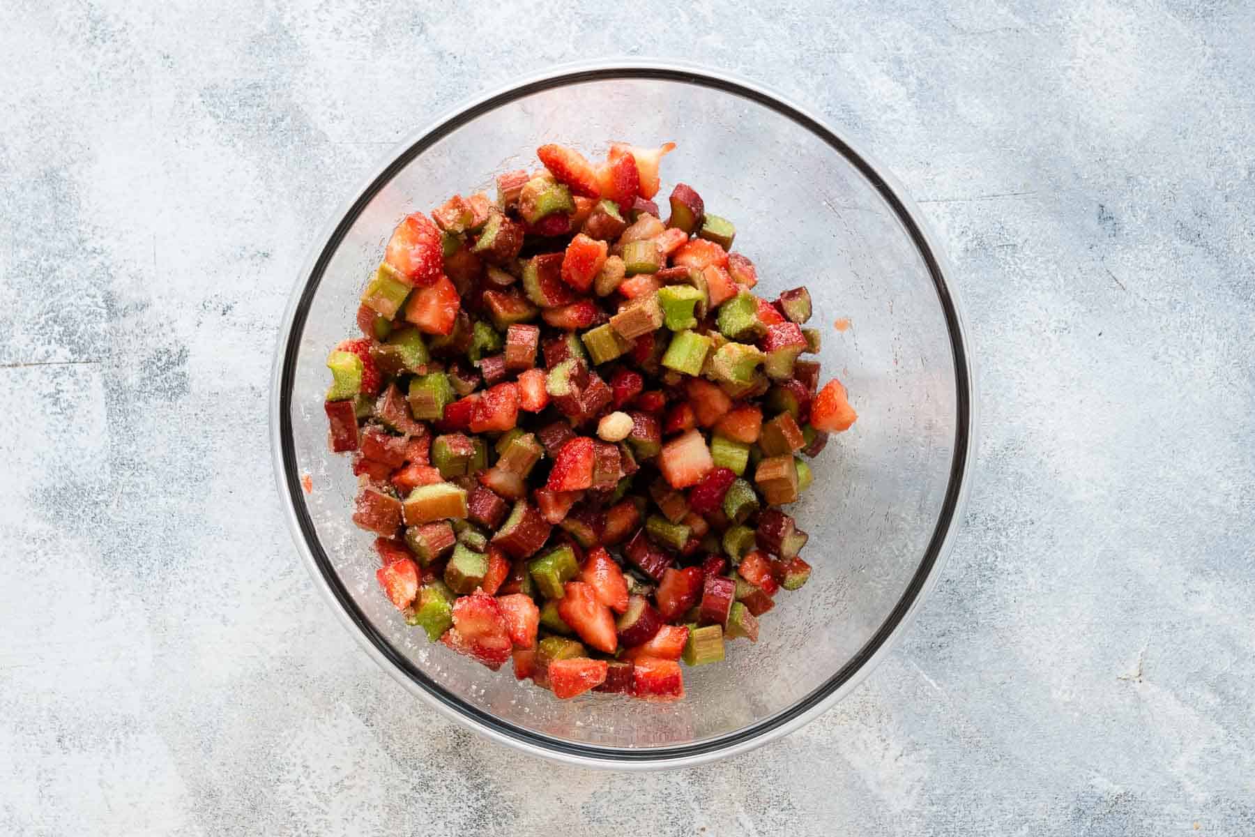 chopped rhubarb and strawberries with sugar in a bowl