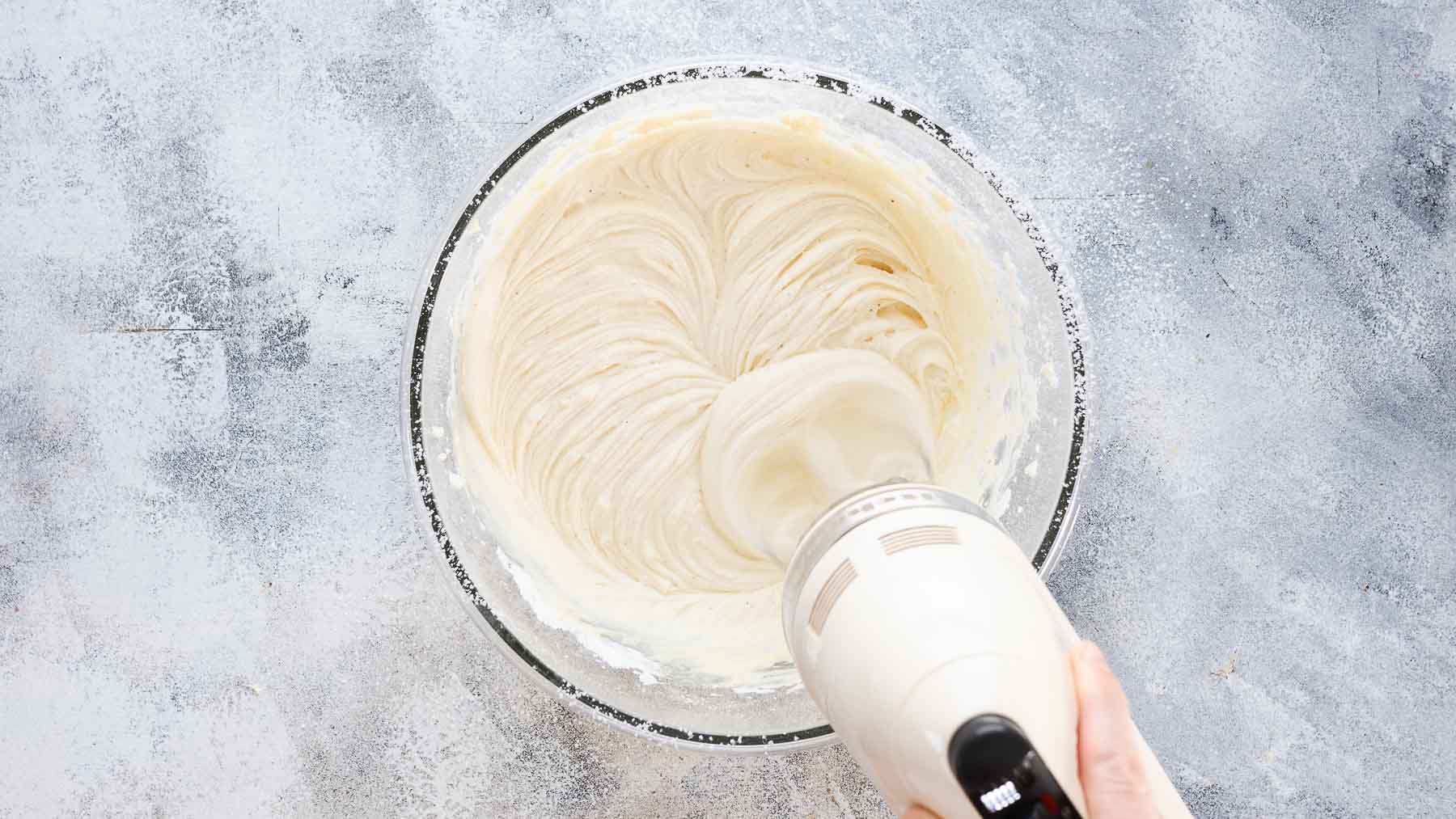 mixing powdered sugar into a butter and cream cheese mixture