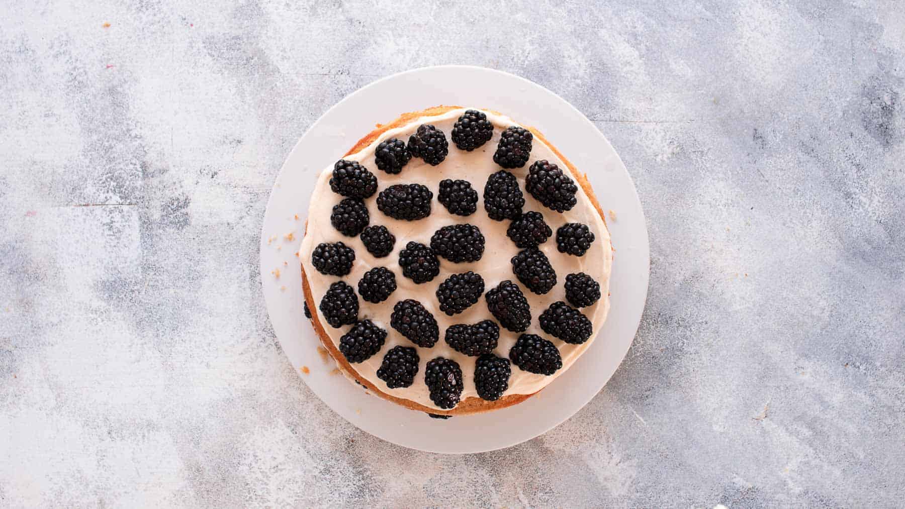 fresh blackberries on top of a frosting layered cake