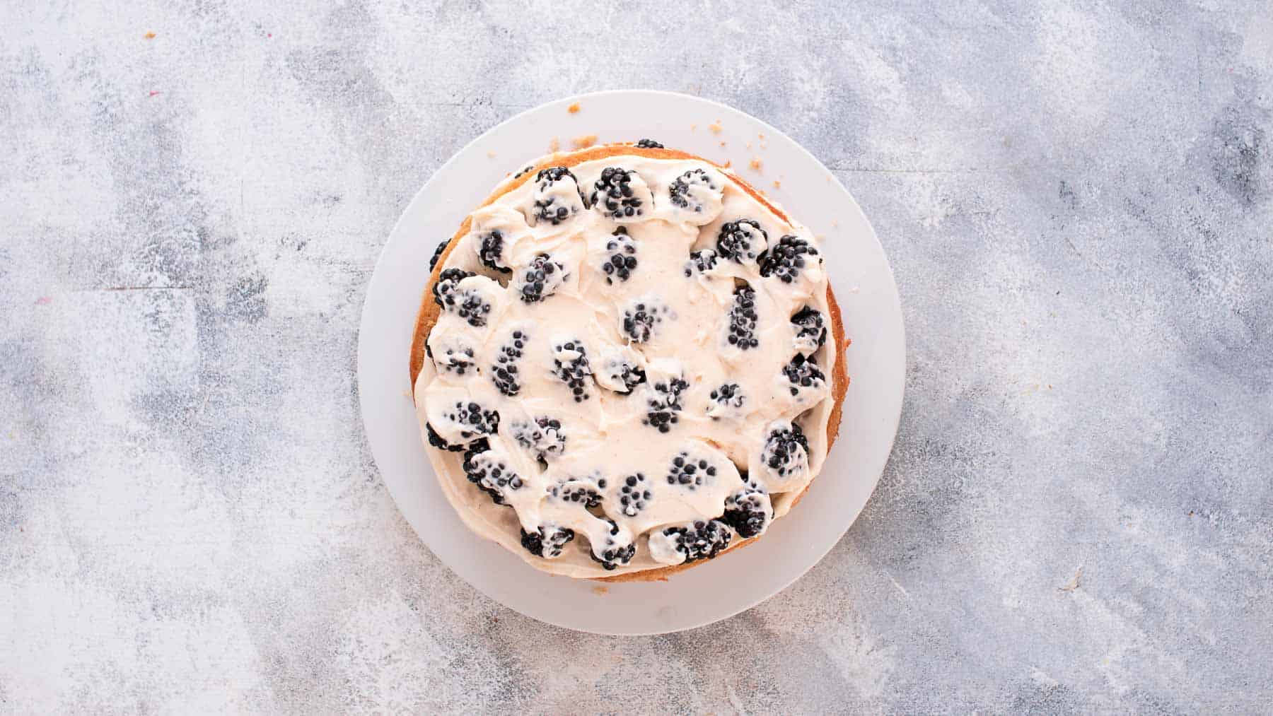 blackberries covered with cream cheese frosting on a cake layer