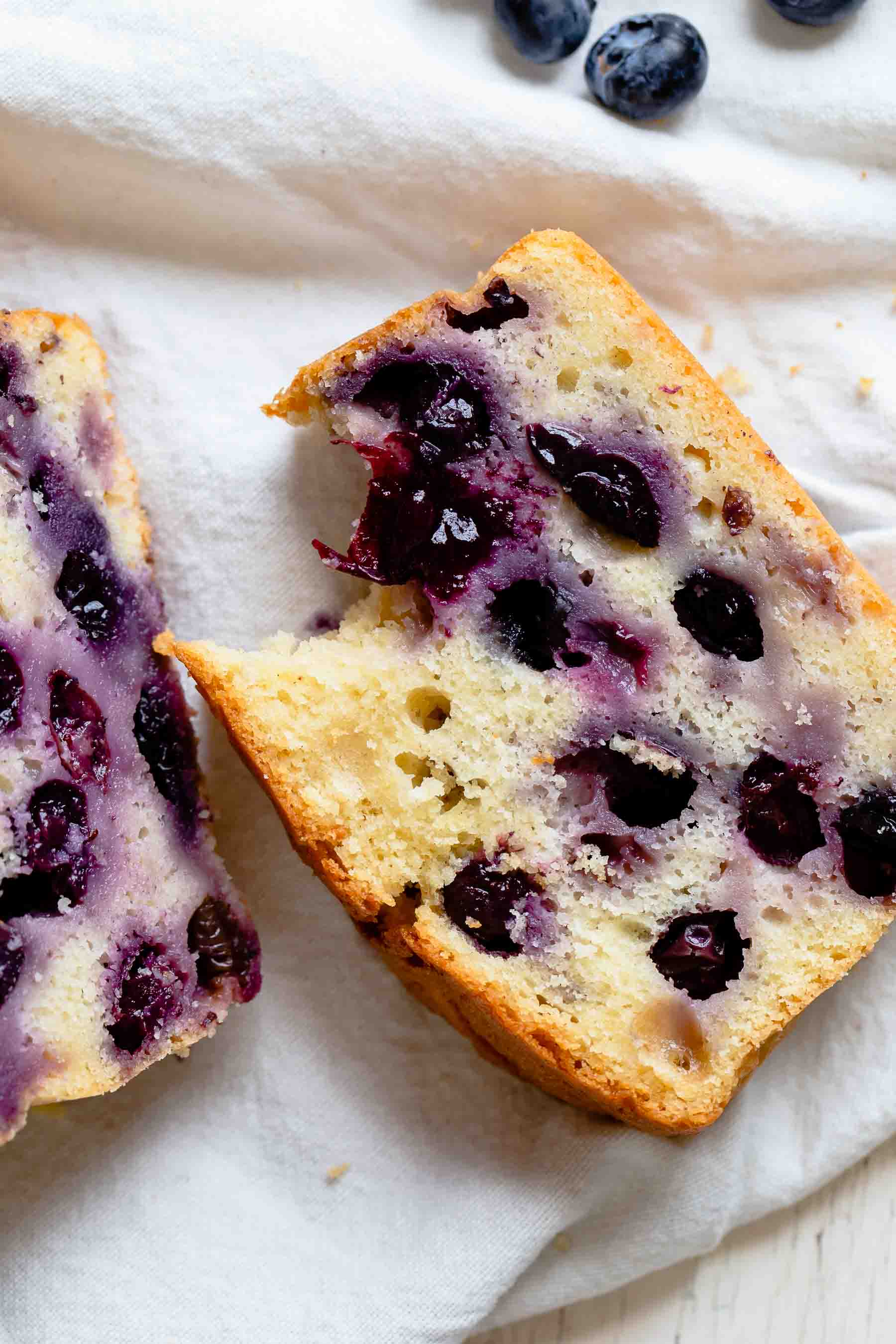 close up of a slice of bitten blueberry bread on a white napkin