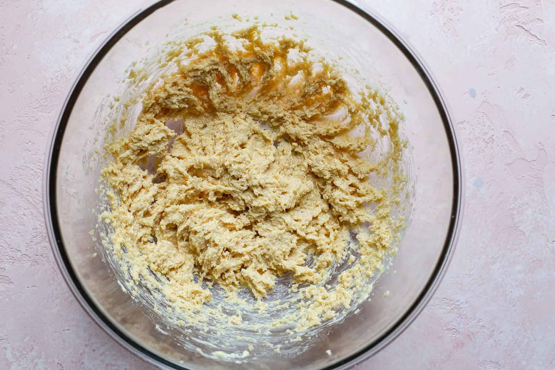 mixed butter, sugar, and spices in glass bowl on pink surface