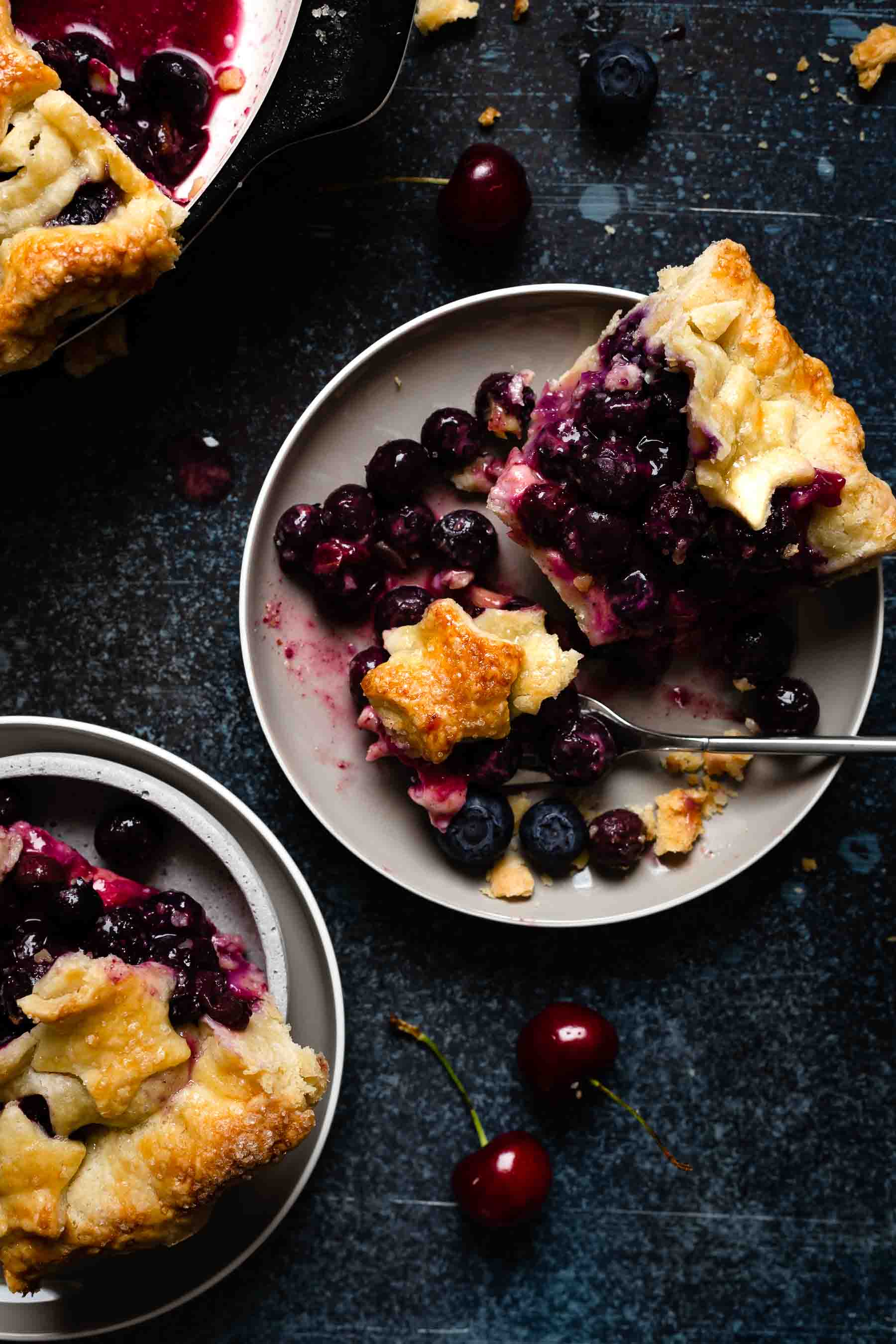 blueberry pie on a plate with a fork full of pie