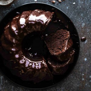 sliced chocolate bundt cake on a black serving plate with a few pieces of cake missing