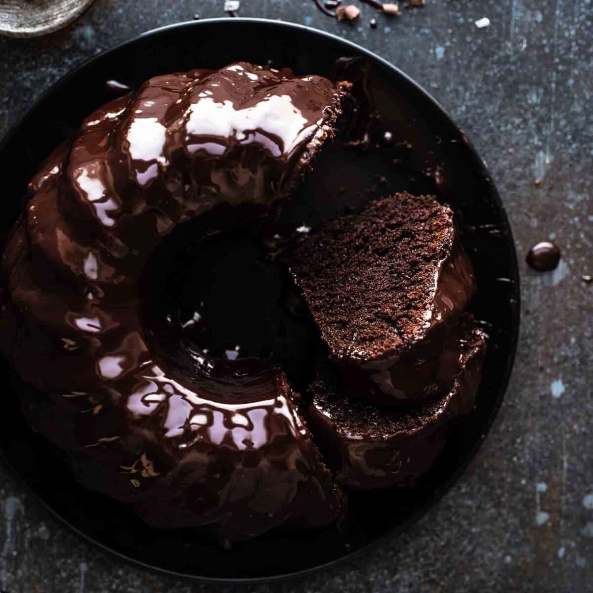 sliced chocolate bundt cake on a black serving plate with a few pieces of cake missing