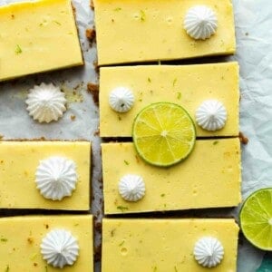 sliced key lime bars on parchment paper with meringue and lime slices on top