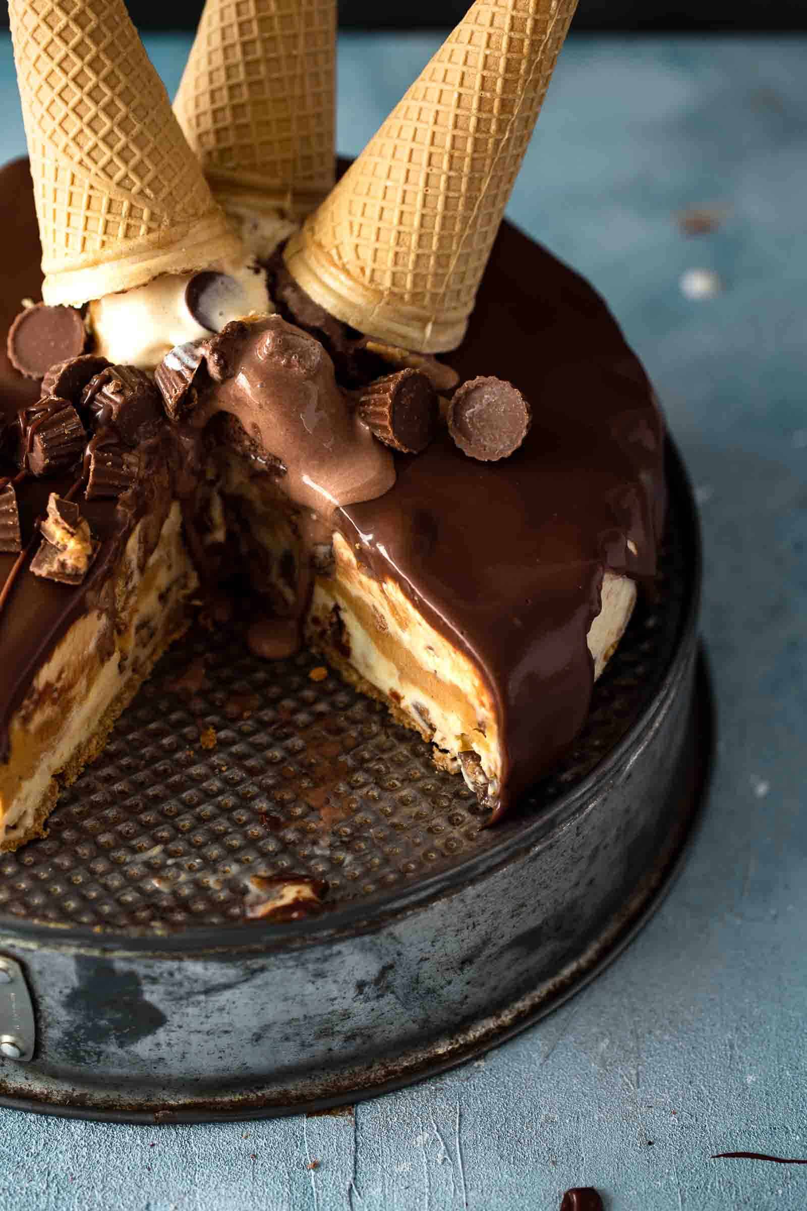 cut ice cream cake on an inverted springform pan topped with ice cream scones and peanut butter cups