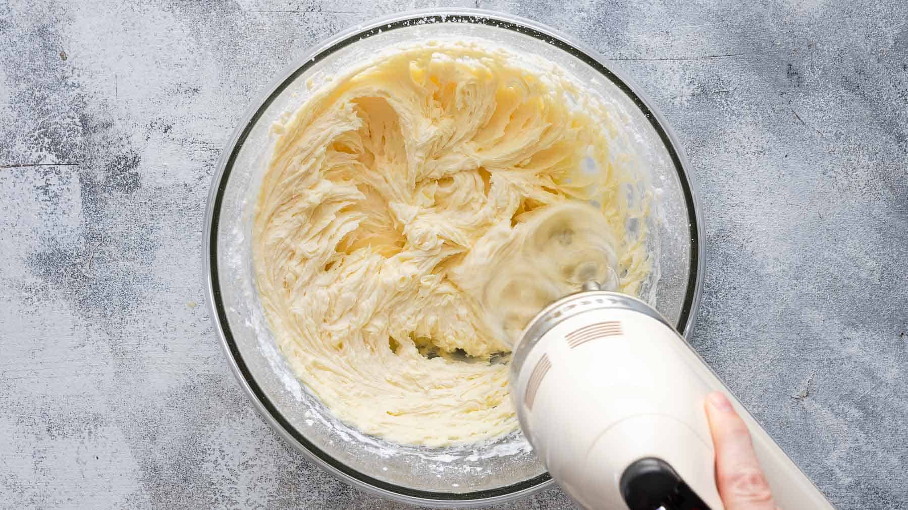 mixing sugar into whipped butter with an electric mixer