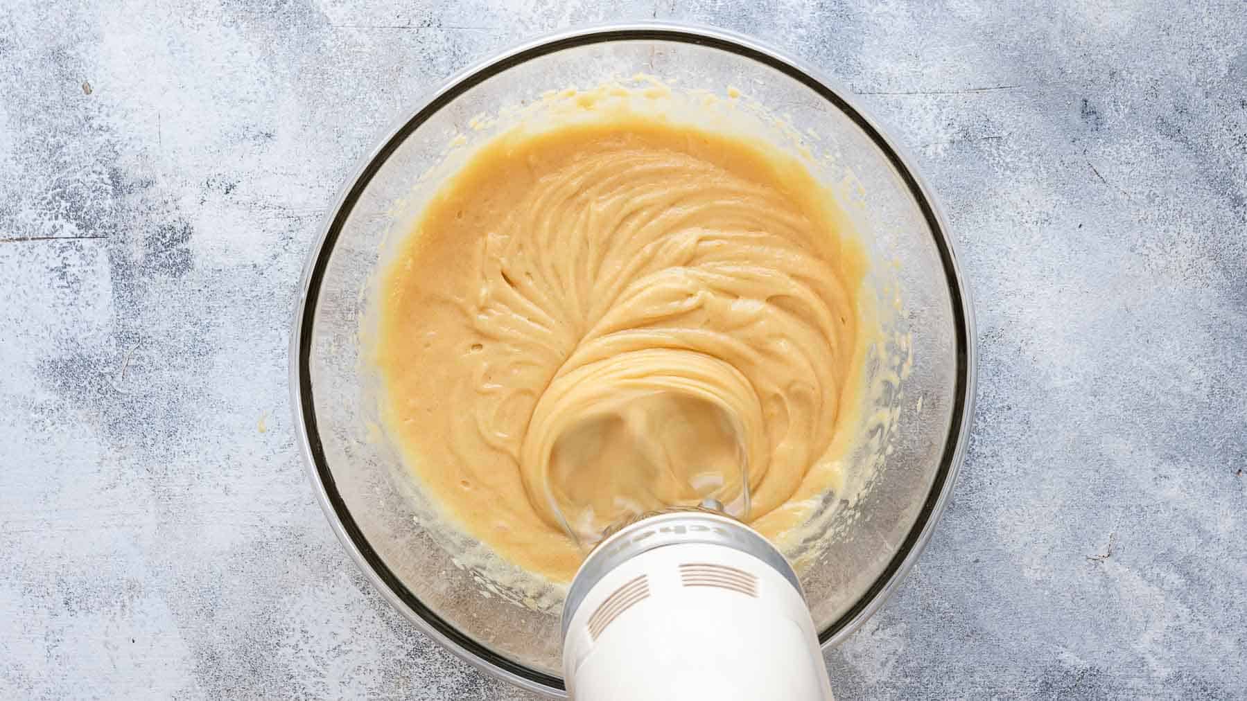 mixing eggs into cake batter with an electric mixer
