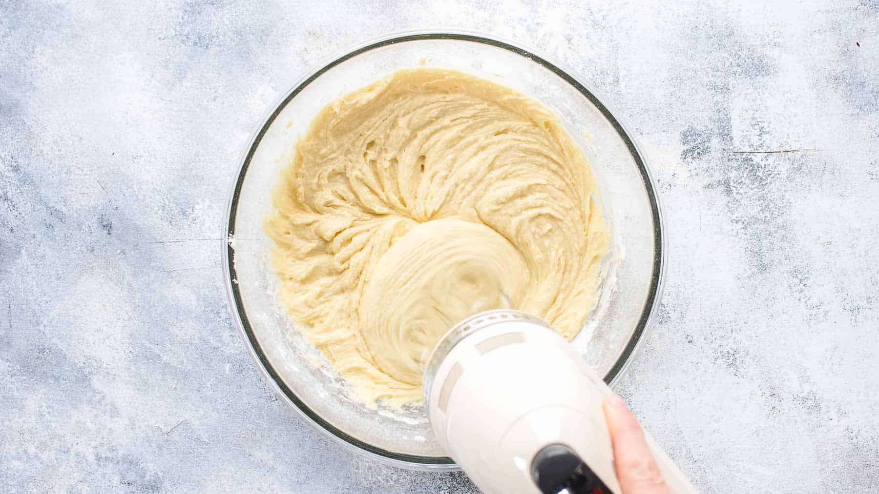 adding flour into batter with hand mixer
