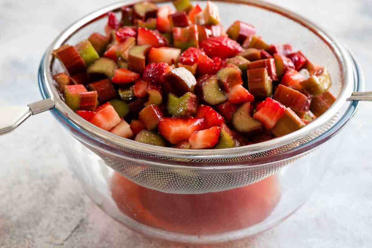 filling for strawberry rhubarb pie in a bowl with strainer