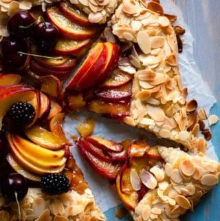 sliced galette filled with peaches and crust covered in toasted almonds