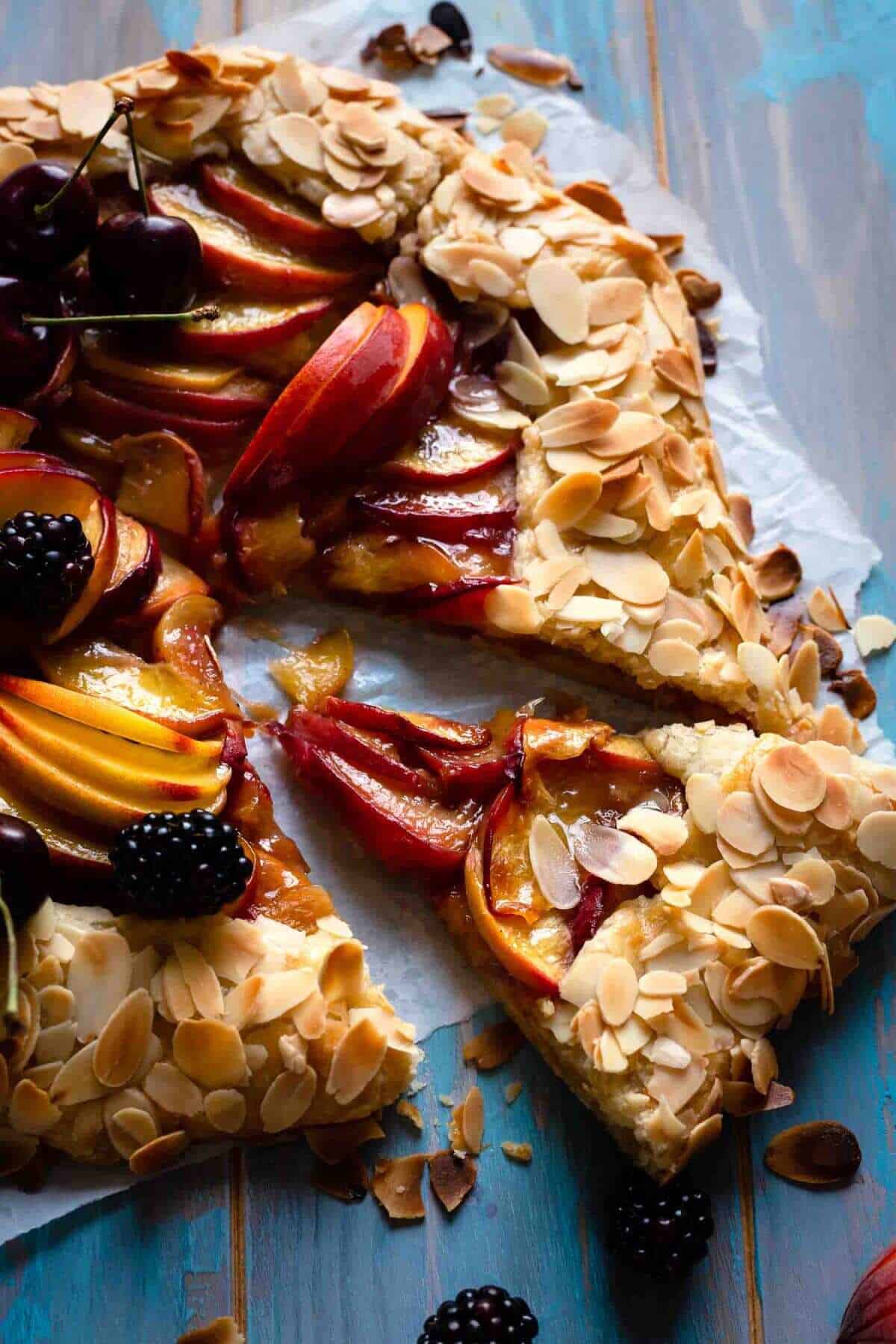sliced galette filled with peaches and crust covered in toasted almonds