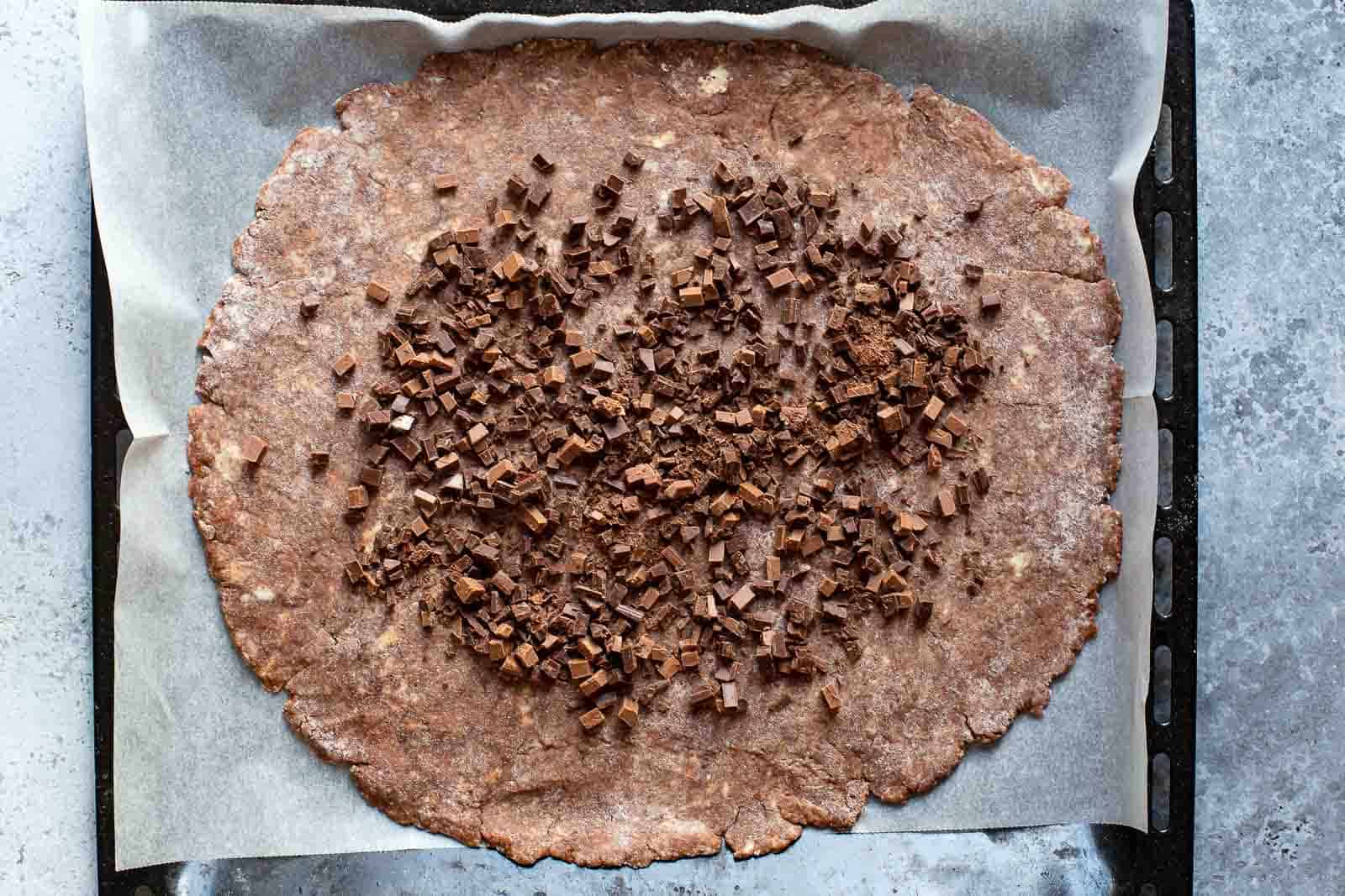 raw chocolate pie dough covered with pieces of dark chocolate
