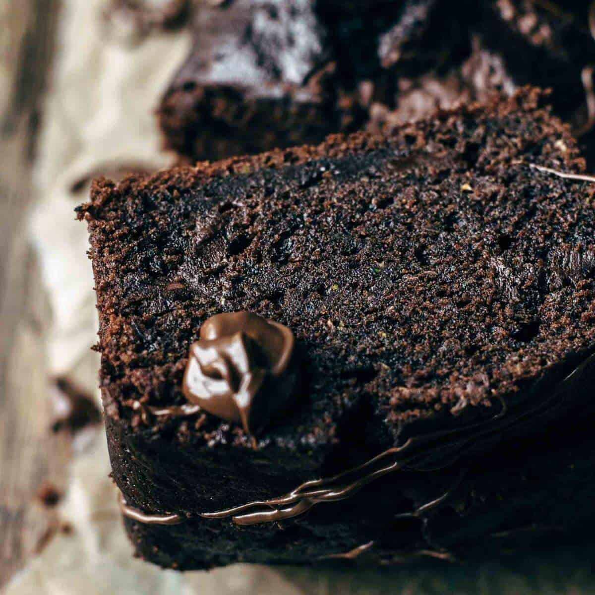 Slices of dark chocolate zucchini loaf with dollops of chocolate spread on top