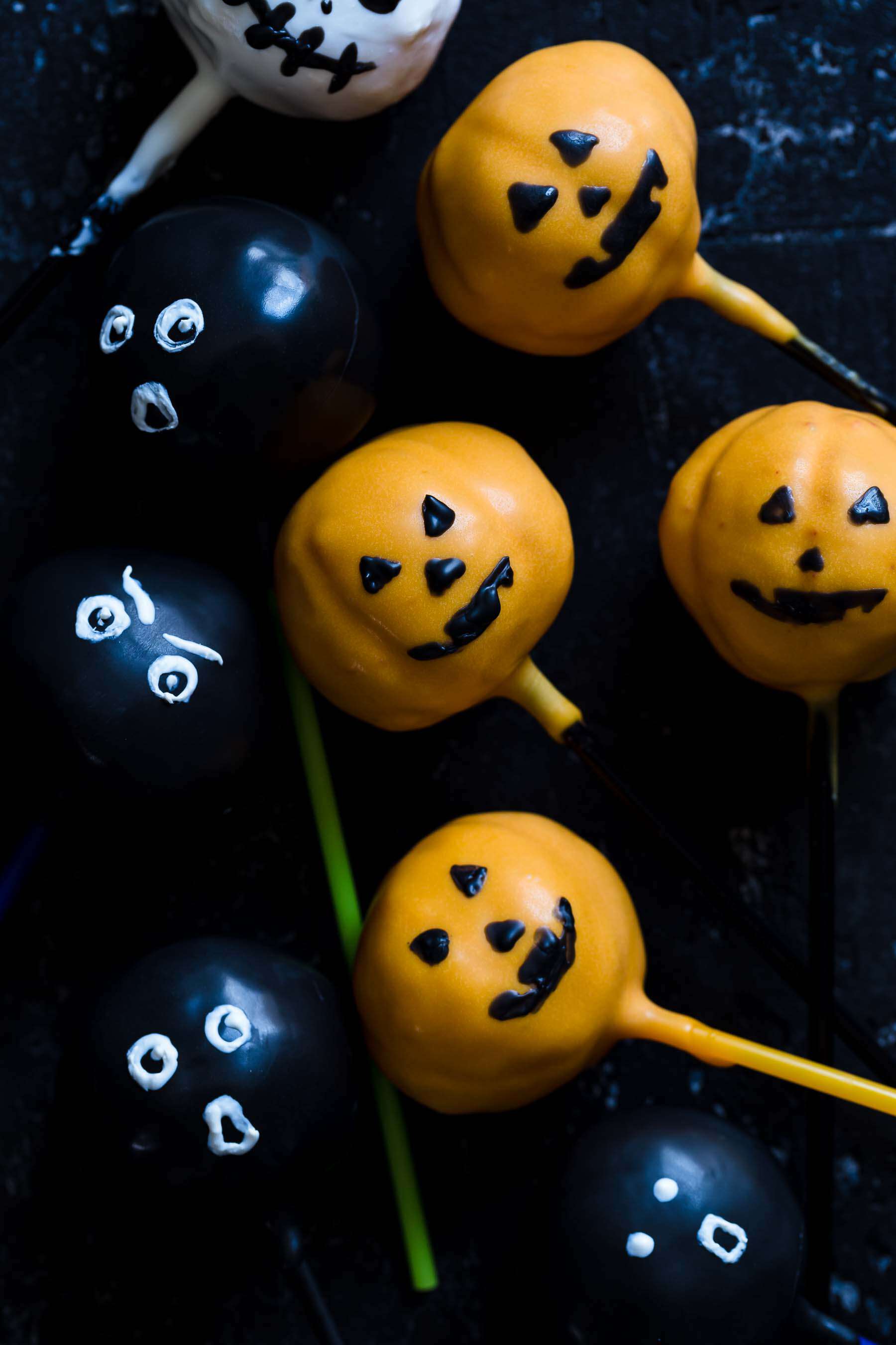 a half dozen cake pops decorated with ghost and pumpkin faces
