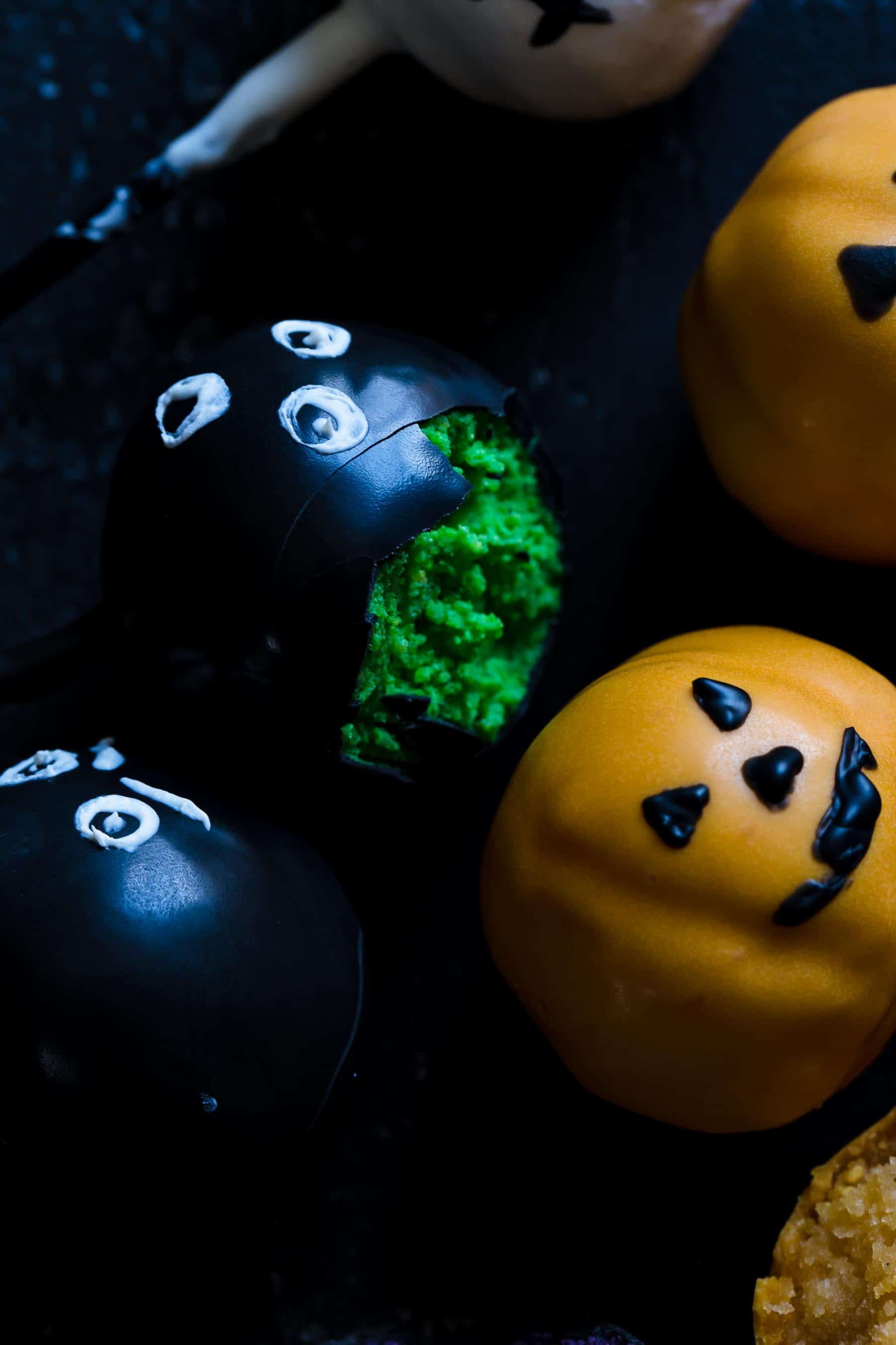 close up of a few decorated black and orange cake pops with one being half eaten