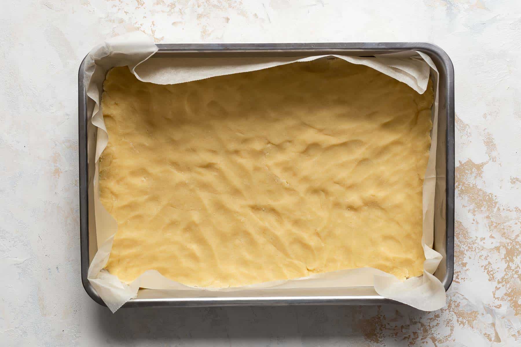 a layer of raw shortbread crust in a baking pan