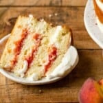 A slice of peach cake on a dessert plate topped with whipped cream