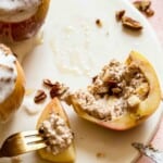 oatmeal stuffed baked apple being half eaten on a white plate