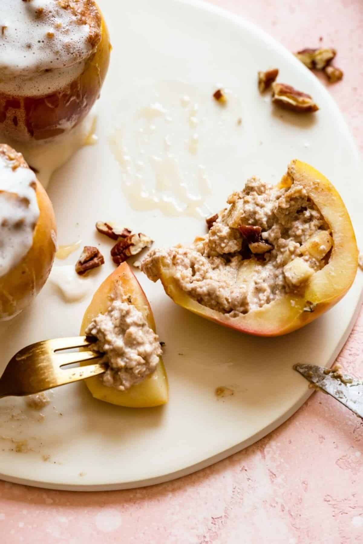 oatmeal stuffed baked apple being half eaten on a white plate