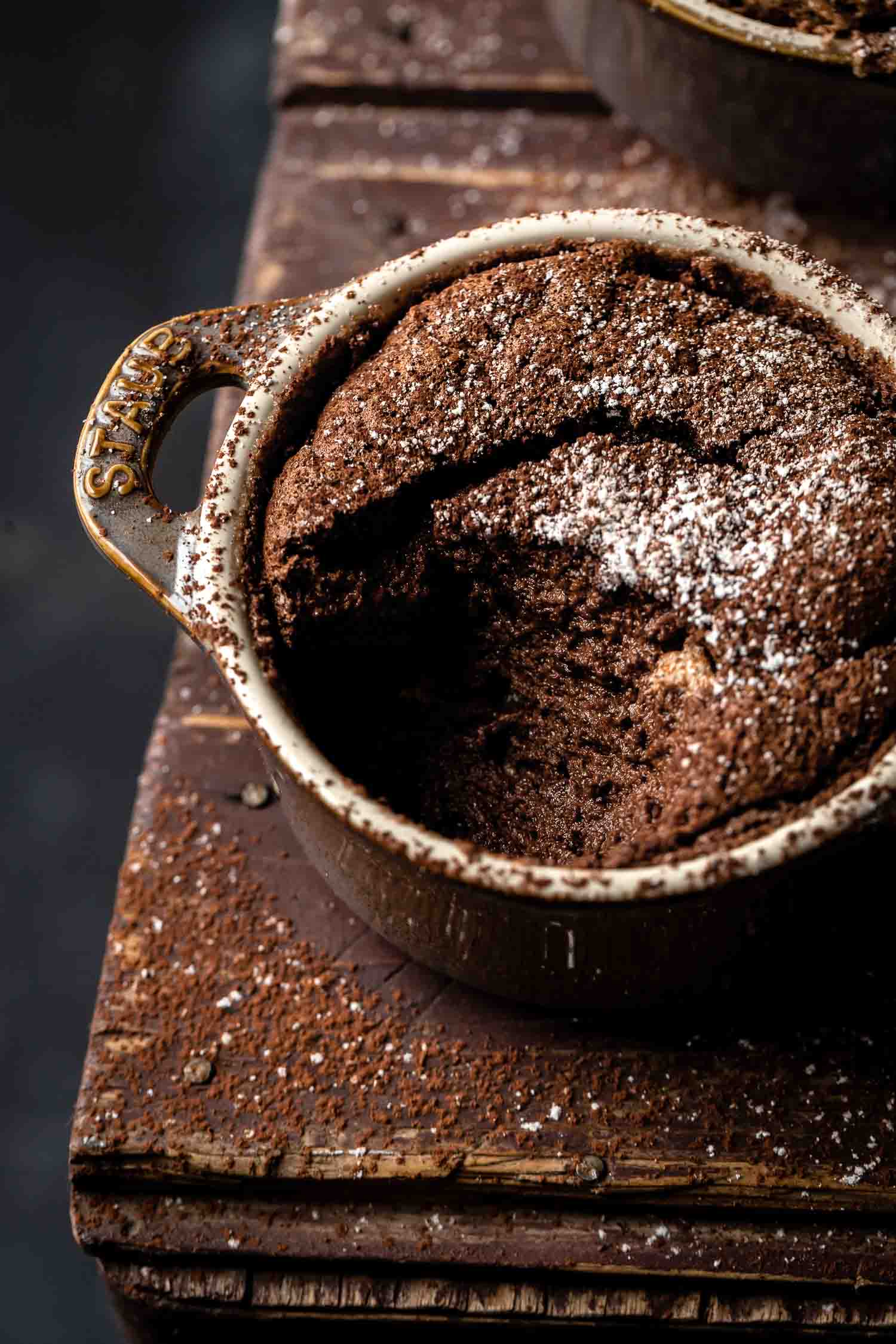 close up of a ramekin full of chocolate soufflé where a bite is missing