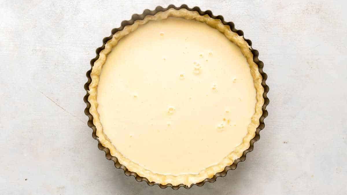 unbaked custard pie in baking pan on white background