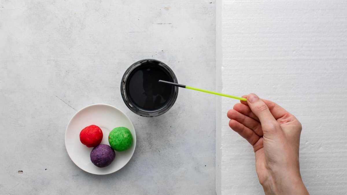 dipping lollipop stick in colored, melted coating