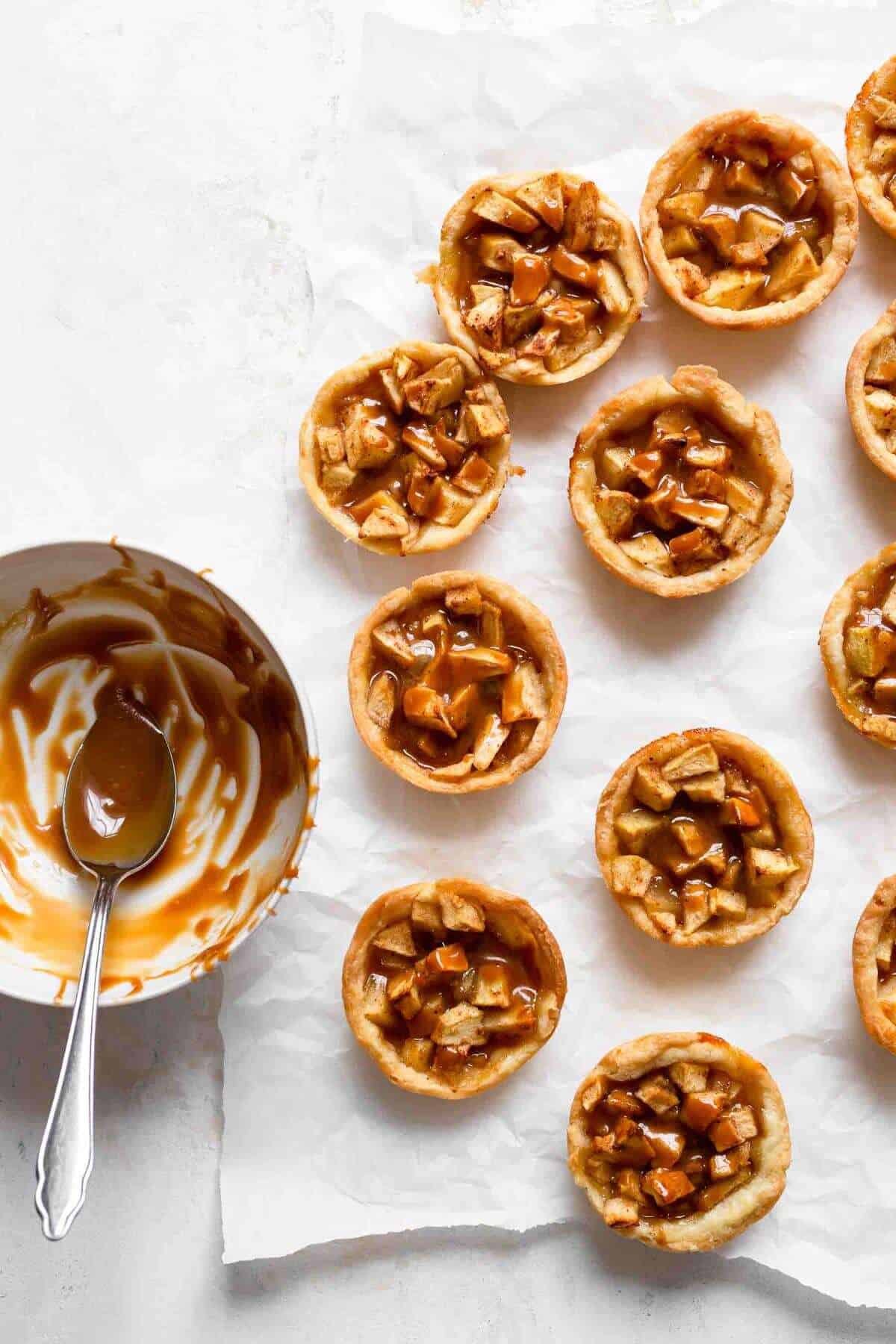 caramel apple mini pies with bowl of caramel beside it