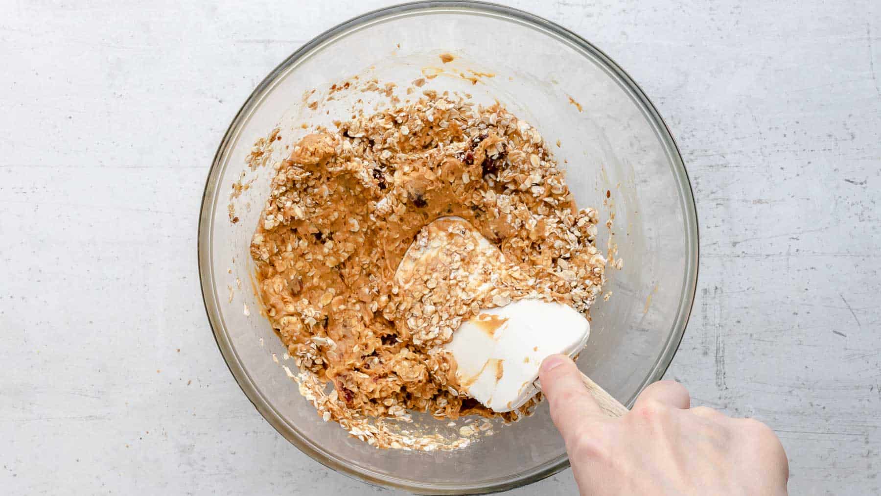 mixing together peanut butter and oats in bowl