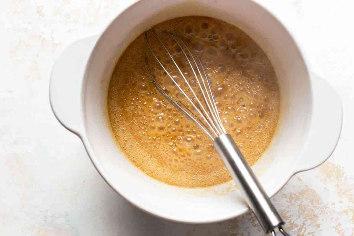 whisk in a bowl with batter for pecan bars