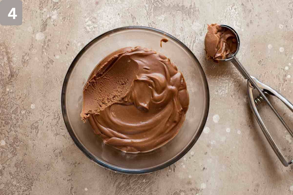 Frozen chocolate truffle mix in a glass dish with an ice cream scoop on the side
