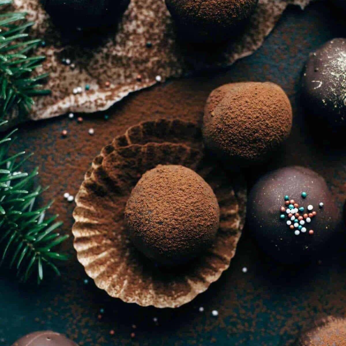 Delicious chocolate rum truffles in a cupcake holder with some sprinkles on top of the surrounding truffles