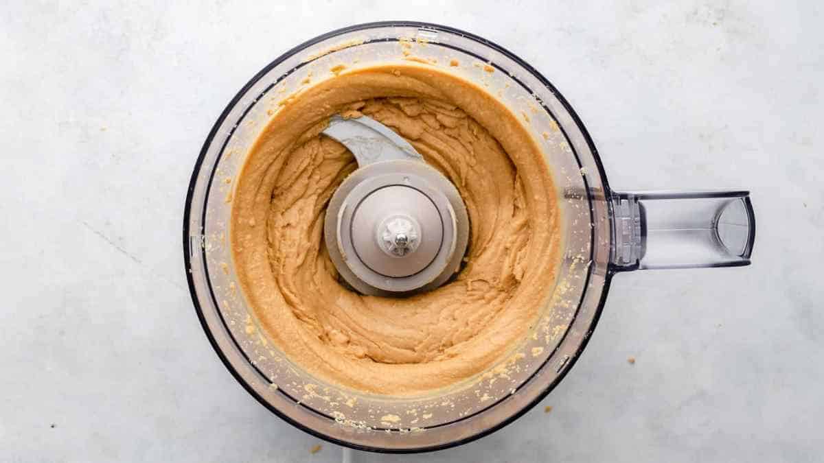 lid off of food processor with peanut butter inside