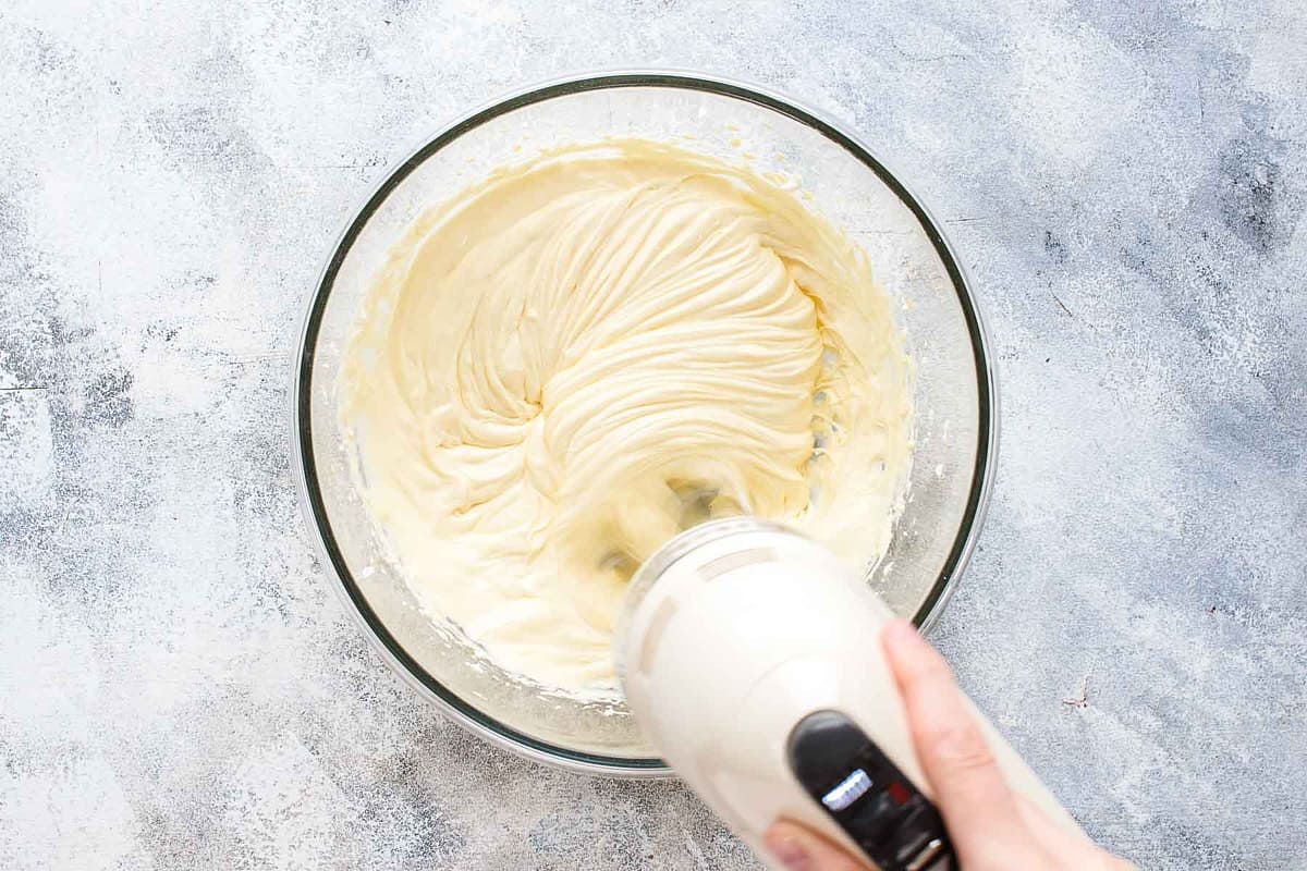 mixing mascarpone, egg yolks, and sugar in glass bowl with mixer