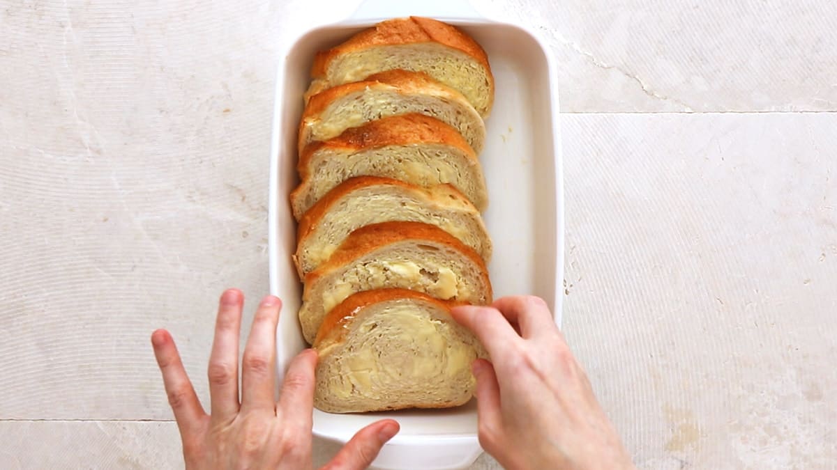 Arranging buttered bread slices in a casserole dish